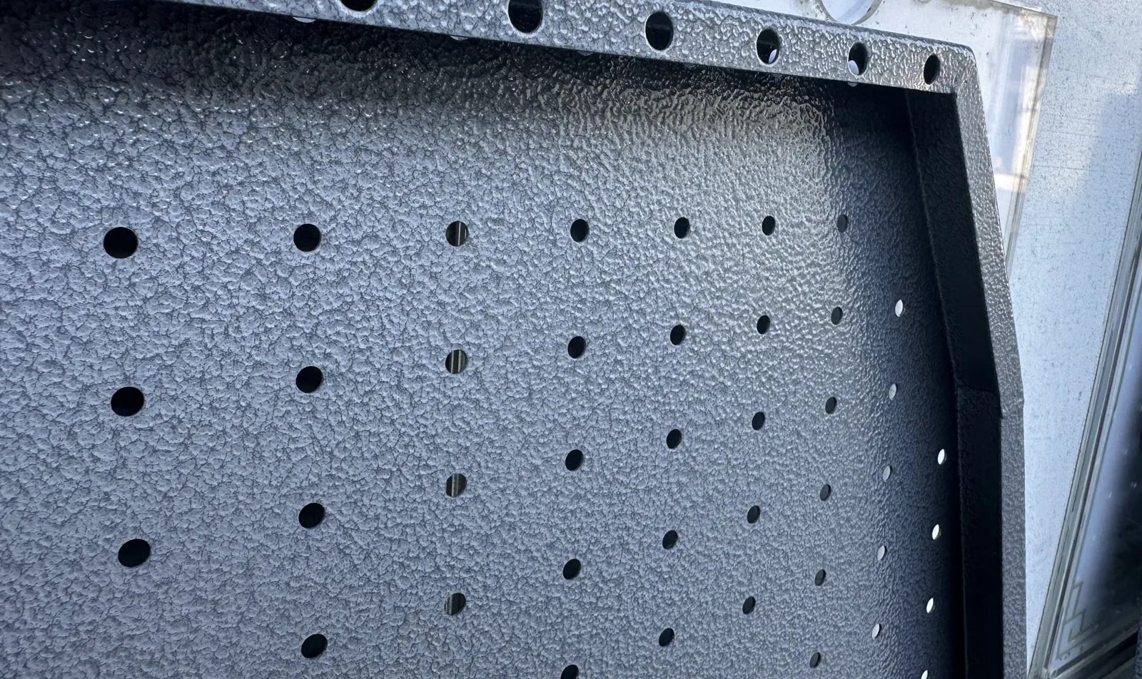 Perforated metal end panel with a textured coating and folded flanges