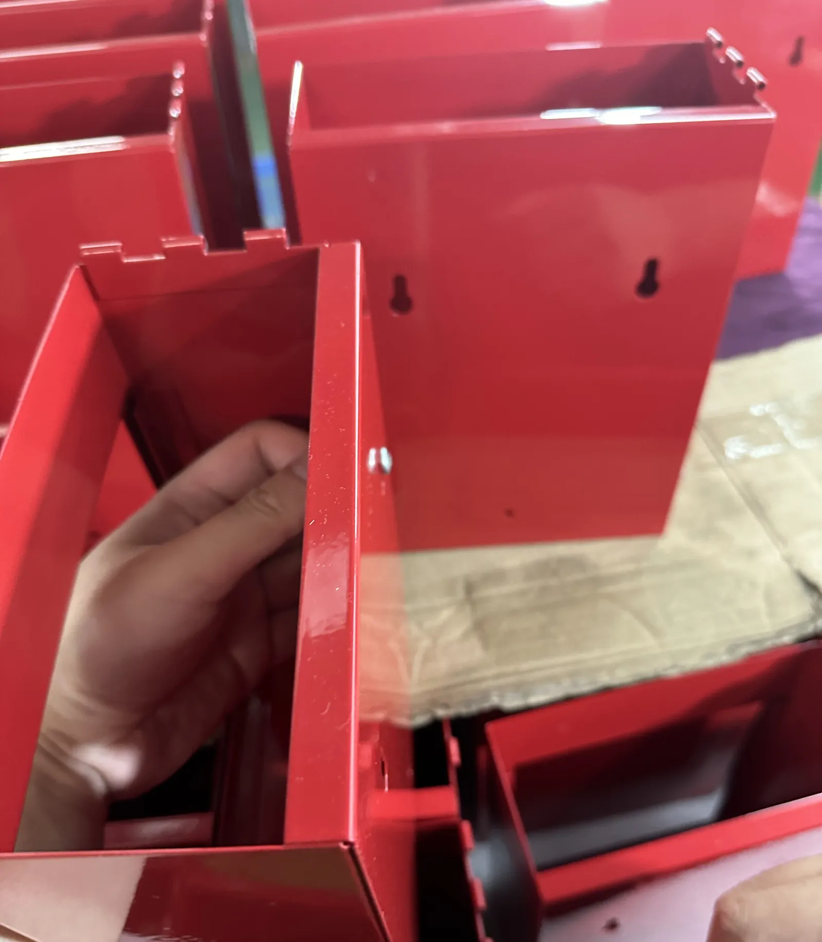 Red metal emergency boxes with keyhole wall-mount slots, checked during production