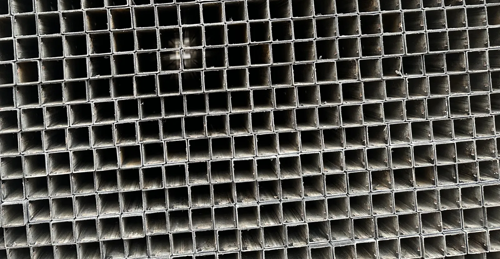 Ends of cut square steel tubes stacked in a bundle at a fabrication factory
