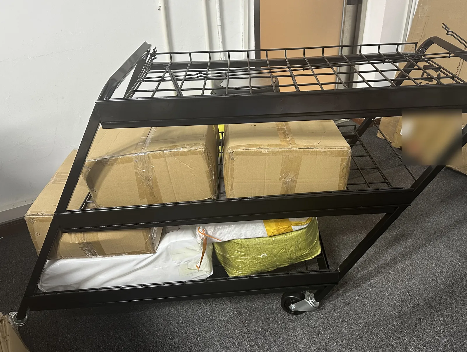 Black wire-basket cart on a square-tube frame with castors, from a volume order Owl Sourcing managed