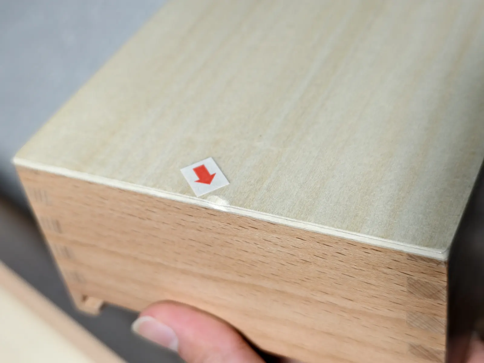 Defect marked with a red arrow sticker on a wooden box during a product inspection